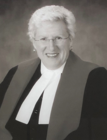 Black and white photo of a female judge wearing glasses. 