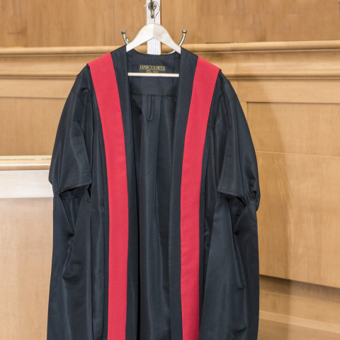 Black and red judicial robes hanging on a hook.