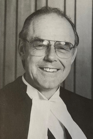 Black and white photo of a man in glasses and judicial robes. 