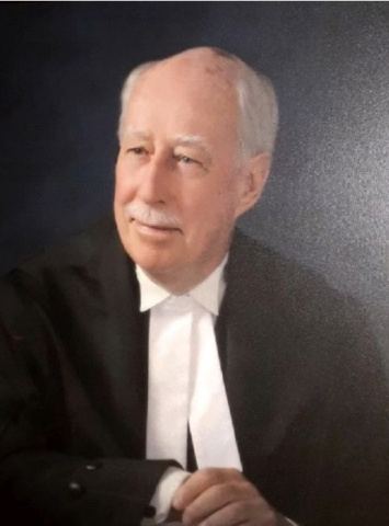 Bald white man with a moustache wearing black and white judicial robes. 