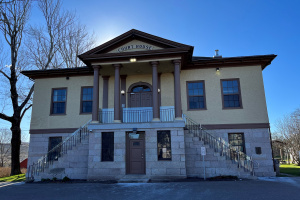 A two-story yellow building with stairs leading to the front door on the second level.