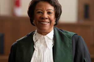 Black woman wearing green, black and white judicial robes. 